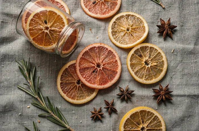 Rondelles d'agrumes déshydratés, citrons et pamplemousses séchés dans un bocal en verre sur fond de lin gris