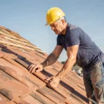 Couvreur professionnel posant des tuiles en terre cuite sur une toiture en pente lors d'une réfection complète