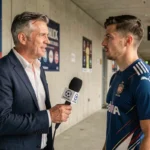 Journaliste sportif interviewant un footballeur professionnel dans le couloir d'un stade lors d'un reportage d'actualité sportive